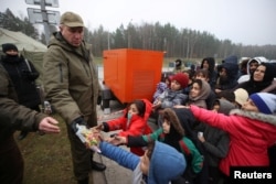 Migranți primesc ajutoare din partea autorităților belaruse, în zona de graniță Bruzgi-Kuznica, regiunea Grodno. Fotografia distribuită de agenția de știri oficială din Belarus, BelTA, 17 noiembrie 2021.