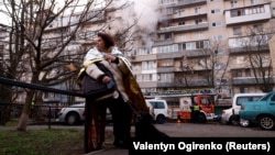 Жінка поруч із багатоповерхівкою, що постраждала внаслідок російської атаки, Київ, 14 листопада 2025 року