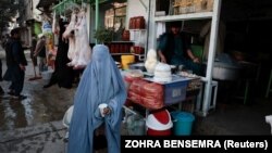 Афганка со стаканом молока, который ей бесплатно дал продавец на рынке в Кабуле
