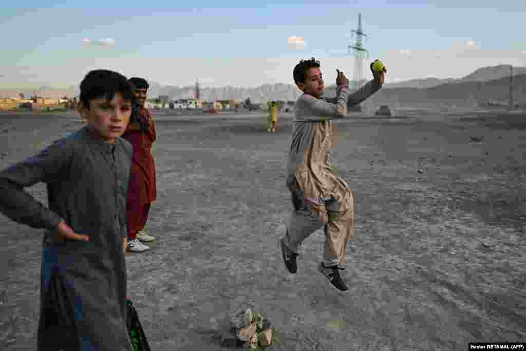 Un copil aruncă o minge în timpul unui joc de cricket, lângă lacul Shuhada din Kabul, Afganistan.