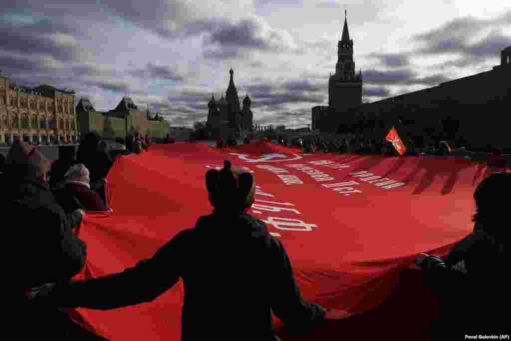 Susținători ai Partidului Comunist poartă un steag uriaș, în timpul marșului către mormântul fondatorului sovietic Vladimir Lenin. Pe 7 noiembrie a fost marcată cea de-a 104-a aniversare a revoluției bolșevice din 1917, în Piața Roșie din Moscova.