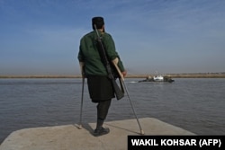A Taliban fighter watches as a barge arrives from Uzbekistan on the Amu River near the Afghan-Uzbek border on October 27.
