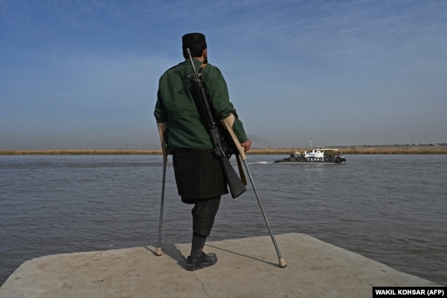 Egy tálib harcos nézi, amint egy bárka érkezik Üzbegisztánból az Amu folyón, az afgán-üzbég határ közelében október 27-én.