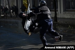 Zyrtari policor duke rrëzuar me mburojën e tij protestuesin 21-vjeçar në Tiranë. Kjo ngjarje nxiti pezullimin e dy zyrtarëve policorë.
