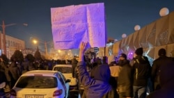 نمایی از یک معترض که پلاکاردی حاوی شعارهای ضد جمهوری اسلامی را در دست گرفته است