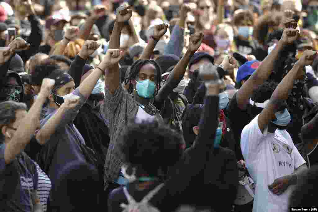Demonstrators raise their arms during a protest against police brutality, Wednesday, June 10, 2020, in Boston, triggered by the death of George Floyd, an African American man who died on May 25 as a Minneapolis police officer pressed his knee into his neck, ignoring his cries and bystander shouts until he eventually stopped moving.