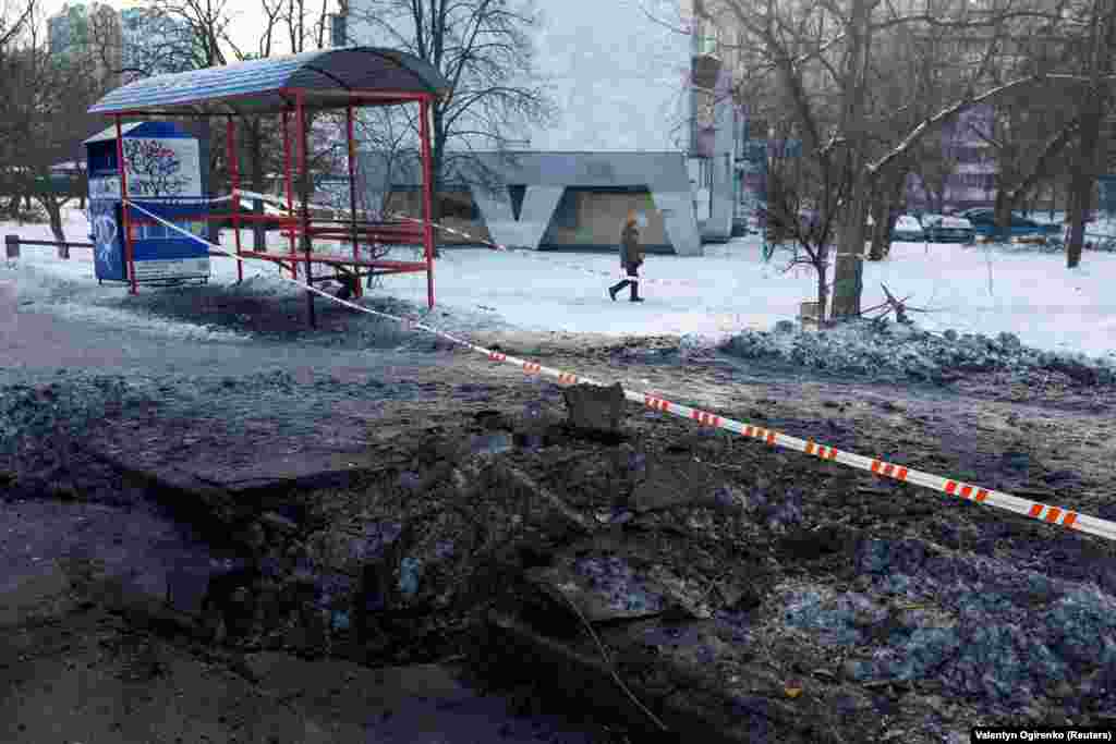 Жителька Києва проходить повз вирву, що утворилася під час нічних ударів російських безпілотників та ракет по Києву. Київ, 24 січня 2026 року