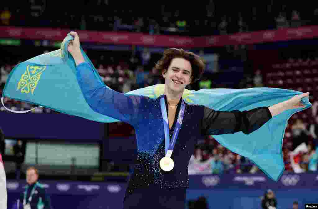 Золотой медалист Михаил Шайдоров из Казахстана празднует победу в одиночном катании среди мужчин с флагом своей страны, Олимпийские игры в Милане и Кортине, 13 февраля 2026 года. REUTERS/Yara Nardi