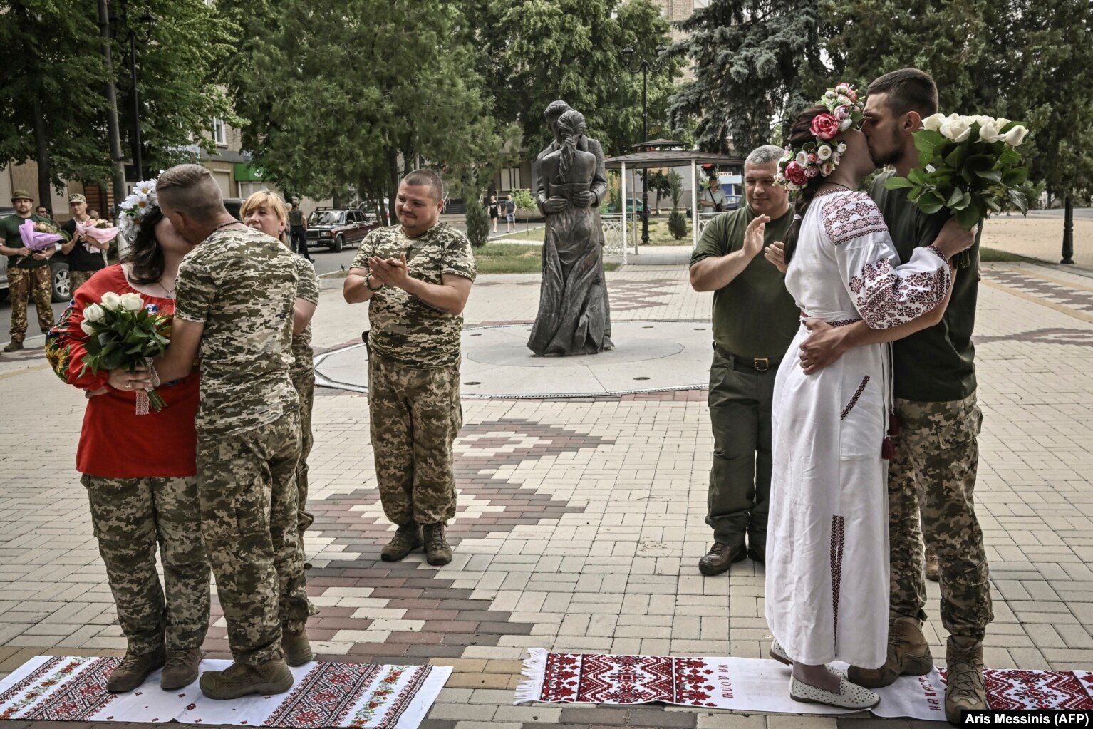 Ushtarët ukrainas martohen pranë monumentit të të dashuruarve (në sfond) gjatë një ceremonie martese në Druzhkivka në qershor 2022.
