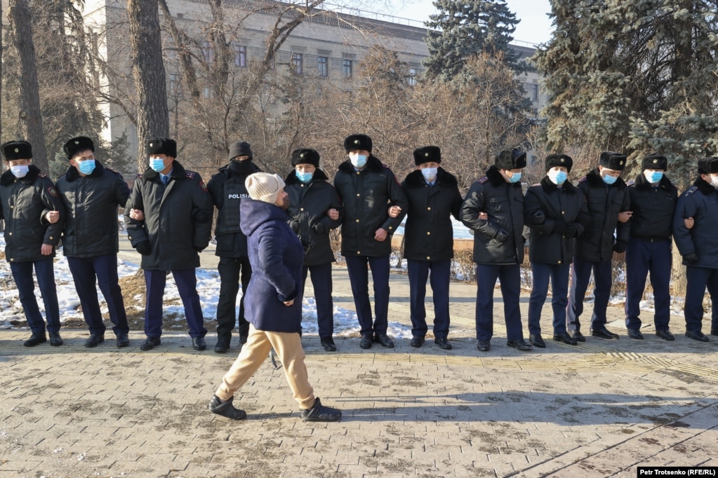 Участница митинга проходит мимо полицейского оцепления. Алматы, 10 января 2021 года.