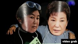 Пратэстоўцы ў Карэі ў масках Пак Кын Хэ (справа) і ейнай сяброўкі Чхвэ Сун Сіль (зьлева)