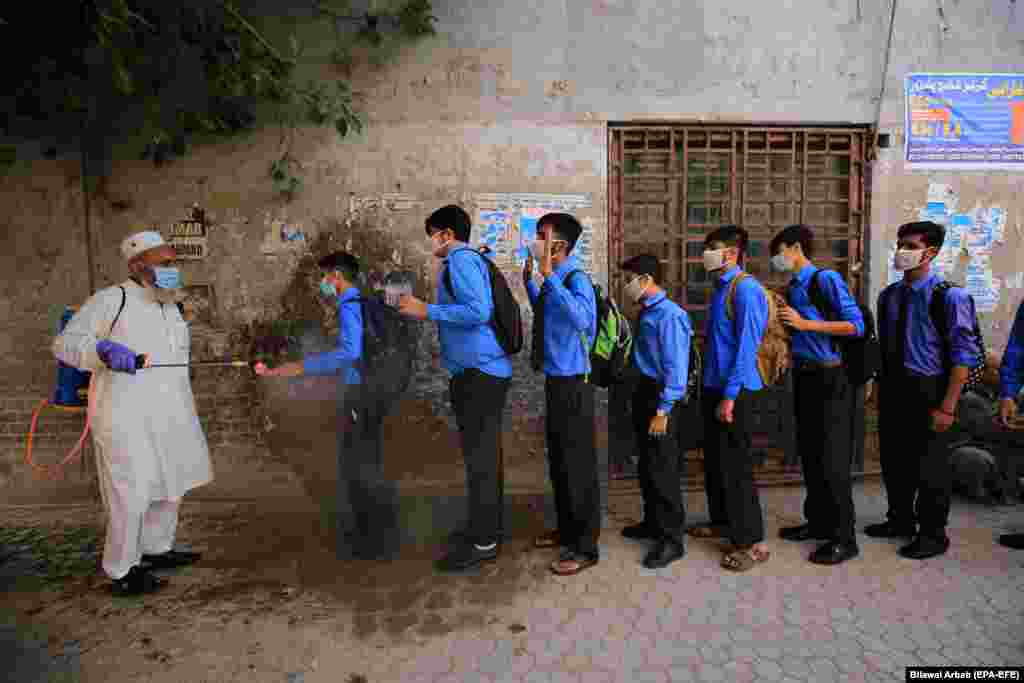 Мугалим окуучулардын колуна дезинфекциялоочу каражат чачып жаткан учуру. Пакистан. 15-сентябрь, 2020-жыл.