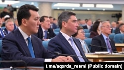 Erlan Karin and Olzhas Bektenov listen to Tokayev's address. September 2025