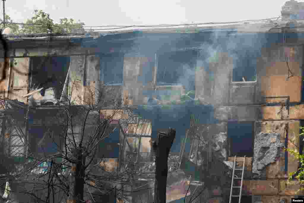 Smoke billows from the burned-out apartment building.