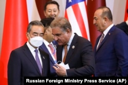 Chinese Foreign Minister Wang Yi (left) listens to Pakistani Foreign Minister Shah Mahmood Qureshi (center) as Turkish Foreign Minister Mevlut Cavusoglu walks by at the Central and South Asia 2021 conference in Tashkent, Uzbekistan, on July 16.