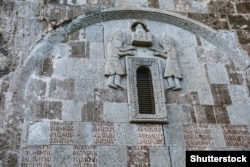 A detail of Dadivank Monastery with Armenian script and carved figures.