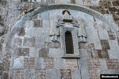 Detaje në Manastirin Dadivank me shkrim armen dhe figura të gdhendura.