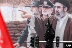 Pripadnik iranskih bezbednosnih snaga na straži pored bilborda sa slikom novog iranskog vrhovnog vođe Modžtabe Hamneija, Teheran, 13. mart 2026.
