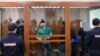 Temirlan Eskerkhanov (left to right), Shadid Gubashev, Zaur Dadayev, Anzor Gubashev, and Khamzat Bakhayev appear inside a defendants' cage in the Moscow military court on June 27.