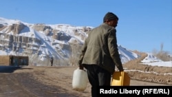 تصویر از مردی در حال بردن آب در نزدیک مغاره های بامیان