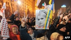 A man flashes a victory signs as he holds a portrait of jailed ex-premier Yulia Tymoshenko during a rally in Kyiv on November 22.