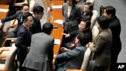 Deputați ai Partidului Democrat de opoziție discutând cu liderul formațiunii, Lee Jae-myung (al treilea din dreapta), în timpul ședinței din 26 decembrie a legislativului de la Seul.