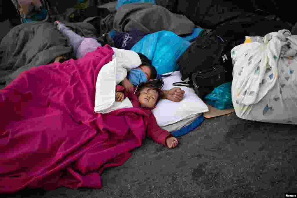 Refugjatët dhe migrantët shihen duke fjetur në qiell të hapur, pas shkatërrimit të kampit.