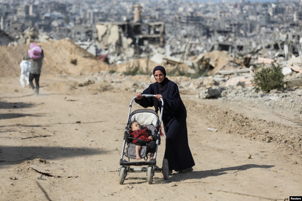 Një grua palestineze me një fëmijë në karrocë në lagjen e saj të shkatërruar në Xhabalia, pas armëpushimit të arritur ndërmjet Izraelit dhe Hamasit.