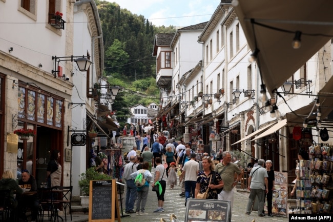 Local residents and tourists walk along a street of Gjirokastra, a UNESCO World Heritage site in southern Albania, on May 7, 2025, ahead of Albania's general election on May 11. Albanians go to the polls on May 11, 2025 for legislative elections seen as crucial to gauge the country's democratic development and determine its widely held goal of a European future. (Photo by Adnan Beci / AFP)