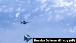 Un avion militar rus Su-27 (jos) face manevre sub un avion NATO F-18 deasupra Mării Baltice