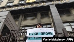 Москвада Думанын имаратынын алдында "Журналист аялдардан колуңарды тарткыла!" деген ураанды көтөрүп турган аял. 21-март, 2018-жыл. 