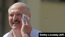 Belarusian President Alyaksandr Lukashenka wipes his face as he addresses supporters on Independent Square in Minsk on August 16.