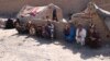 An internally displaced Afghan family sits outside a temporary shelter as they await relief from the authorities on the outskirts of Herat.