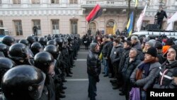 Police stand guard in front of protesters during a demonstration in support of EU integration in front of the parliament building in Kyiv on December 3.