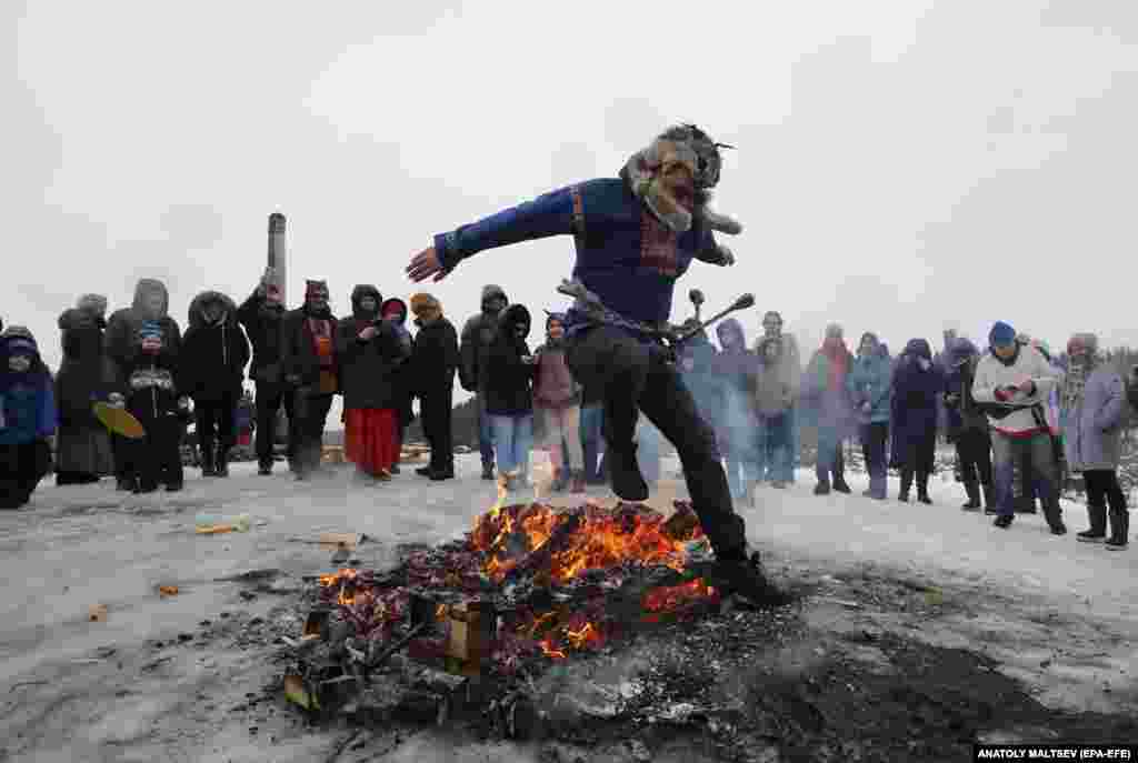 Russians jump over the charred remains of an effigy of Lady Maslenitsa outside St. Petersburg.