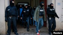 Полиция арнайы жасағы терроризм күдігімен тексеру жүргізген үйден шығып келеді. Берлин, 16 қаңтар 2015 жыл.