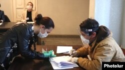 Nagorno-Karabakh -- A voter (L) and an election commission official at a polling station in Stepanakert, March 31, 2020.