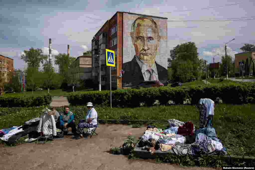 Ulični prodavci prodaju odeću i cveće u blizini stambenog bloka na kojem je mural aktuelnog predsednika Vladmira Putina u Kaširi u moskovskoj regiji (Reuters/Maxim Shemetov)