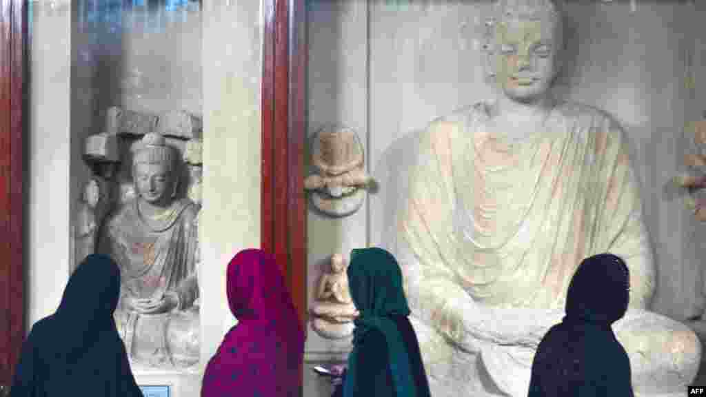 Young women look at statues of Buddha on display in a museum at Taxila in Pakistan&#39;s Punjab Province.