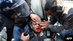 An injured riot police officer is cared for by colleagues in the center of Belgrade.