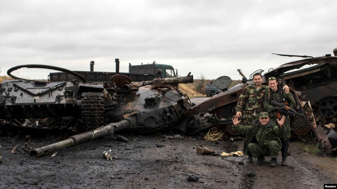 Pro-Russian rebels pose for a picture next to the burnt-out remains of a Ukrainian tank near the village of Novokaterinovka, eastern Ukraine on September 24.