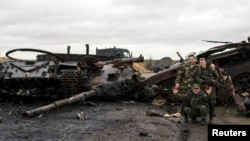 Pro-Russian rebels pose for a picture next to the burnt-out remains of a Ukrainian tank near the village of Novokaterinovka, eastern Ukraine on September 24.