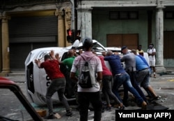 Ljudi guraju prevrnuti automobil na ulici u okviru demonstracija protiv kubanskog predsednika, Havana 11. jula 2021.