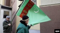 Demonstrators outside the Turkmen Embassy in Moscow hold a Turkmen flag with a black ribbon.