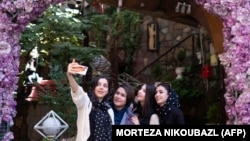 Tinere iraniene își fac un selfie (fără hijab) în fața unei terase din cartierul Darband din Teheran.