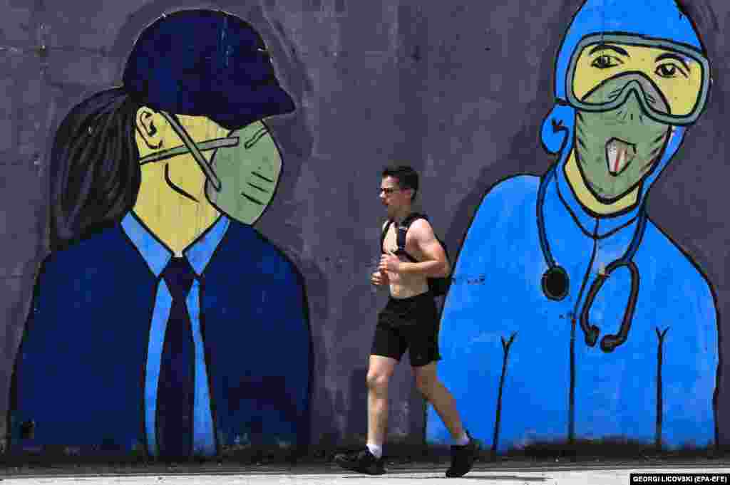 A man runs in front of a mural inspired by the coronavirus pandemic in Skopje, North Macedonia. (epa-EFE/Georgi Licovski)