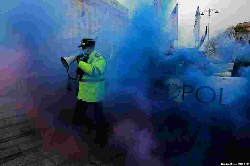 A police officer walks through colored smoke while shouting slogans during a protest demanding better pay and conditions for cops in front of the Romanian Interior Ministry on March 25. (epa-EFE/Bogdan Cristel)