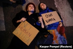 A lengyel kormány által bevezetett szükségállapot ellen tiltakozók fekszenek az utcán a varsói parlament előtt, 2021. szeptember 6-án. "Egyetlen ember sem illegális" és "Meg fognak halni" olvasható a feliratokon.