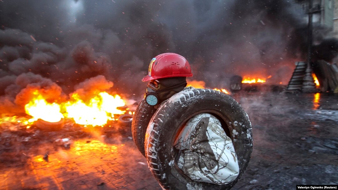 A day after intense clashes between protesters and riot police left at least three people dead, activists in Kyiv on January 23 set fire to tires and barricades, filling the streets with smoke.