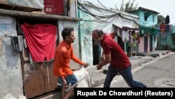 A plainclothes policeman wields his baton against a man as a punishment for breaking the lockdown rules, after India ordered a 21-day nationwide lockdown to limit the spreading of coronavirus disease (COVID-19), in Kolkata on March 25.